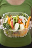 Woman holding plastic container of sliced vegetables