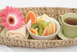 Cup of tea, fresh fruit, towel and flower in basket