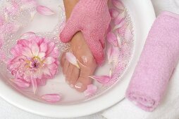 Woman washing her foot with pink peeling glove