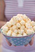 Frau hält Popcorn in Schale mit Sterndeko (4th of July, USA)