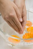 Woman dipping her hands in soapy water with marigolds