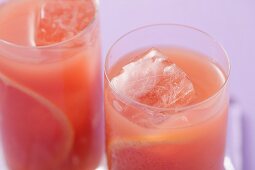 Two glasses of pink grapefruit juice with ice cubes
