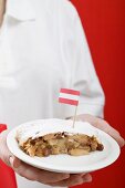Woman holding piece of apple strudel with Austrian flag on plate