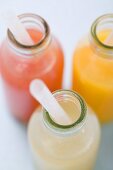 Three fruit juices in bottles with straws (overhead view)