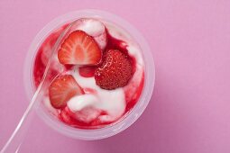 Erdbeerjoghurt im Plastikbecher mit Löffel (Draufsicht)