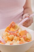 Woman taking spoonful of fruit salad out of bowl