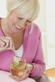 Woman putting tea bag into cup of hot water