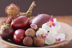 Verschiedene exotische Früchte in einer Schale mit Orchideen