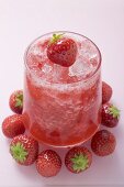 Fruchtiger Erdbeerdrink, umgeben von frischen Erdbeeren