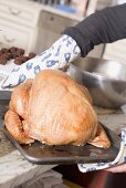 Carrying stuffed turkey to oven on baking tray