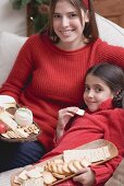 Woman and girl on sofa with cheeseboard and crackers