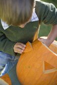 Small boy making pumpkin lantern