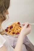 Woman eating cornflakes with raspberries