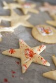 Plätzchen mit Zuckerstreuseln auf Backpapier