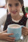 Girl holding large mug of cocoa with pieces of candy cane