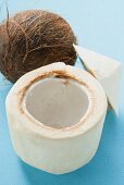 The flesh of a coconut in front of whole coconut
