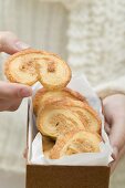 Hand taking palmier (puff pastry biscuit) from box