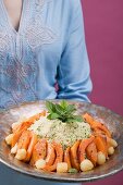 Woman serving couscous with pumpkin, mint and onions