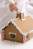 Child decorating gingerbread house with piping bag