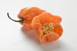 Orangefarbene Habanero Chilischoten, ganz und halbiert