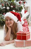 Woman in Father Christmas hat beside Christmas gifts