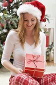 Woman in Father Christmas hat looking at Christmas gift