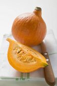 Hokkaido pumpkins (whole and quarter) on tea towel, knife