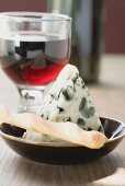 Piece of blue cheese, savoury stick and glass of red wine