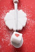 Heart-shaped sugar lumps in a circle, sugar cube on spoon