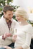 Man & woman clinking glasses of sparkling wine (Christmas)