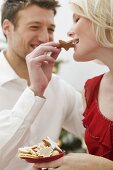 Man feeding Christmas biscuit to woman
