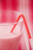 Strawberry milk in glass with straw (close-up)