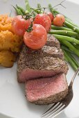 Beef steak, a slice cut off, with cherry tomatoes