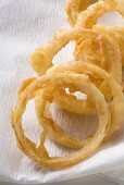 Deep-fried onion rings on kitchen paper (close-up)