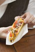 Woman holding mince taco in paper napkin