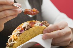 Woman putting sauce on mince taco