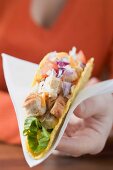 Woman holding chicken taco on paper napkin