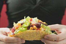 Frau hält Taco mit Gemüsefüllung