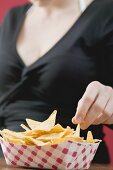 Woman reaching for nachos in cardboard container