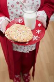 Woman holding Christmas cookies and glass of milk on plate