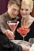 Waiter serving two drinks to romantic couple