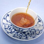 Tee in Tasse einschenken