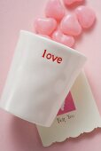 Pink heart-shaped sweets, beaker and Valentine card
