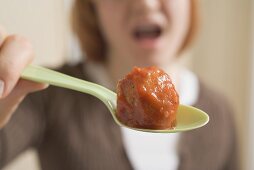 Woman holding meatball on spoon