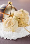 Almond biscuits on icing sugar in front of Christmas bauble