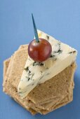 Piece of blue cheese with red grape on crackers