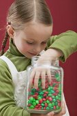 Small girl reaching into jar of chocolate beans