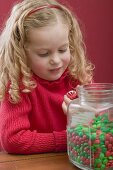 Small girl holding peppermint, jar of chocolate beans