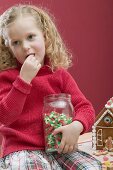 Small girl eating candy corn out of sweet jar