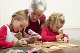 Grandmother & two granddaughters decorating Christmas biscuits